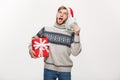 Holiday Concept - young beard man holding a christmas gift box and money over white background Royalty Free Stock Photo