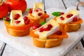 Crostini appetizers with persimmons, pomegranates and brie, close up on white platter