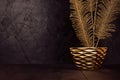 Holiday dark interior in vintage style with decorative golden warm branch in glossy modern bowl on wood board, black plaster wall.