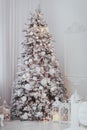 Holiday decorated room with Christmas tree covered with snow and toys. White interior with lights. Royalty Free Stock Photo