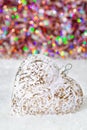 Glass heart on a snow and blurred colorful background of glittering bokeh with glowing lights. Christmas decoration. Copy space Royalty Free Stock Photo