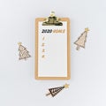 Holiday decorations and clipboard with wish list 2020 on white background, flat lay