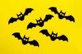 Holiday decorations for Halloween. Five black paper bats on a yellow background, top view
