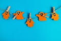 Holiday decorations for Halloween. Orange paper ghosts hanging on a rope on a blue background with copy space