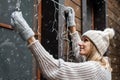 Holiday decorations. woman install electric christmas string lights on house exterior facade Royalty Free Stock Photo