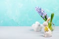 White ceramic bunny, decorative Easter eggs, jacinth on white table. Turquoise backdrop. Copy space.