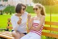 Holiday with the family. Happy young mother and cute daughter teenager in city park eating ice cream, talking and laughing Royalty Free Stock Photo