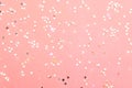 Holiday festive glitter background with pattern from scattered sparkling golden silver stars on pink backdrop. New Years Christmas