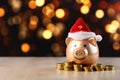 Holiday finance with a piggy bank wearing a Santa hat, surrounded by coins, against a backdrop of festive bokeh lights. Savings