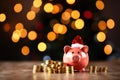 Holiday finance with a piggy bank wearing a Santa hat, surrounded by coins, against a backdrop of festive bokeh lights. Savings