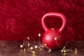 Holiday fitness, red kettlebell with gold star twinkle lights, against a red background