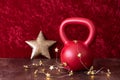 Holiday fitness, red kettlebell with gold star twinkle lights, big gold star, against a red background Royalty Free Stock Photo