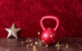 Holiday fitness, red kettlebell with gold star twinkle lights, big gold star, against a red background Royalty Free Stock Photo