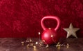 Holiday fitness, red kettlebell with gold star twinkle lights, big gold star, against a red background