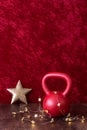 Holiday fitness, red kettlebell with gold star twinkle lights, big gold star, against a red background Royalty Free Stock Photo