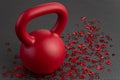 Holiday fitness, red kettlebell, with red heart confetti, on a black gym floor