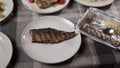 Holiday food delivery. Grilled mackerel fillet is placed on a white plate from disposable tableware, setting the table