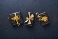 Holiday gift box or present with ribbon, golden confetti and gold baubles on black background. Magic christmas greeting card. Chri Royalty Free Stock Photo