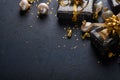 Holiday gift box or present with ribbon, golden confetti and gold baubles on black background. Magic christmas greeting card. Chri Royalty Free Stock Photo