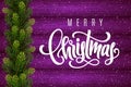 Holiday gift card with hand lettering Merry Christmas and fir tree branches on wood background Royalty Free Stock Photo