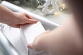 Holiday gifts. A woman wraps a present under a Christmas tree in silver paper.