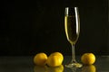 holiday glass of champagne wine tangerines golden candle fire Christmas toys dark black background Royalty Free Stock Photo