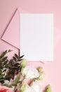 Holiday greeting card mockup with envelope and white flowers on pink background, top view, flat lay. Blank wedding invitation card Royalty Free Stock Photo