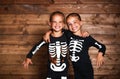 holiday halloween. funny funny sisters twins children in carnival costumes skeleton on wooden . Royalty Free Stock Photo