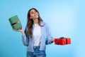 Excited young beautiful girl holding gift boxes isolated on blue studio background. Concept of emotions, Merry Christmas Royalty Free Stock Photo