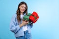 Excited young beautiful girl holding gift boxes isolated on blue studio background. Concept of emotions, Merry Christmas Royalty Free Stock Photo