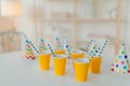 Holiday hats and paper cups with beverage and straws on white table. Festive event. Birthday party celebration concept. Blurred
