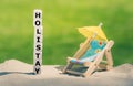 Holiday at home. Dice form the word holistay next to a beach chair Royalty Free Stock Photo