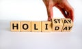 Holiday at home symbol. Male hand turnes cubes and changes the word `holiday` to `holistay`. Beautiful white background. Copy