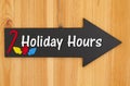 Holiday Hours type message on hanging arrow chalkboard sign with a candy cane and lights