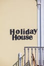 Holiday house. Hotel words text posted on the exterior wall. Near the railing of a balcony. Yellow wall