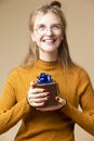 Holiday Ideas. Surprised Caucasian Blond Female Girl with Tiny Golden Yellow Gift Christmas Box In Round Glasses Holding Present Royalty Free Stock Photo