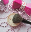 Powder and powder brush on a background of pink accessories