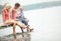 Holiday, lake and family with kids with foot in water during summer vacation in the outdoor. Deck, parent and child at Royalty Free Stock Photo