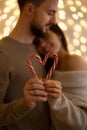 couple kissing and showing the heart-shaped figure of candy canes candies