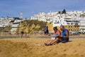 Holiday makers relaxing in the sun on the beach at the Old Townin Albuferia, Portugal Royalty Free Stock Photo