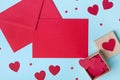 Holiday mockup for Valentines day. Box full of red hearts and paper card with envelope on blue table top view. Flat lay style. Royalty Free Stock Photo