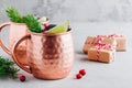 Holiday Moscow Mule ice cold Cocktail in copper cup with cranberries, lime and rosemary on stone background