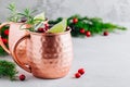 Holiday Moscow Mule ice cold Cocktail in copper cup with cranberries, lime and rosemary on stone background