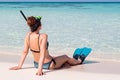 Picture from back of a young woman with flippers and mask seated on a white beach in the Maldives. Crystal clear blue water as Royalty Free Stock Photo
