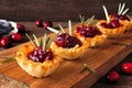 Holiday phyllo pastry appetizers with cranberries and baked brie. Side view serving board against wood.
