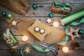 Holiday preparation, wrapping gifts with natural paper and green ribbon, Christmas decoration like balls, stars and lit candles on Royalty Free Stock Photo