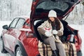 Holiday presents. Beautiful young woman is outdoors near her red automobile at winter time Royalty Free Stock Photo