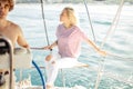 Woman on white yacht in nautical theme in open sea. Blond hair and blue clothes.