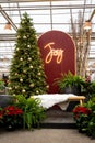 Holiday scene with a gold decorated Christmas tree, Joy sign, and bench for seating