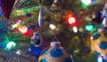 Holiday season, Christmas tree decorations glow under luminous and vivid, colorful lights on a small faux indoor tree. Royalty Free Stock Photo